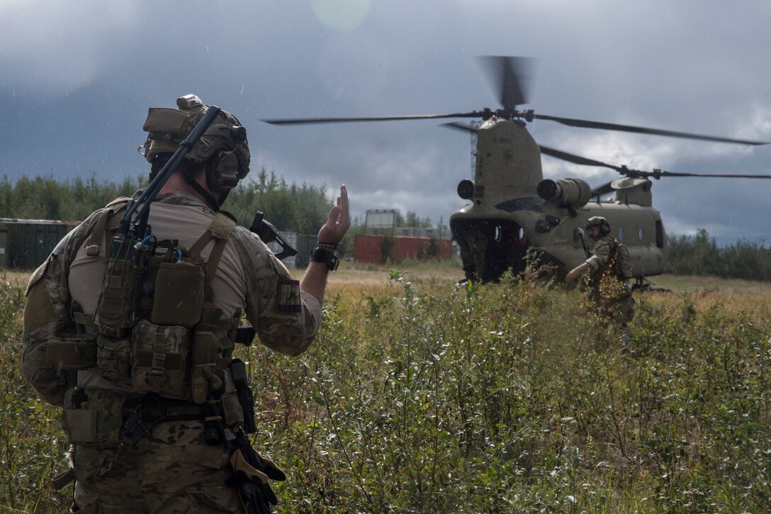 man stands in a field signaling to incoming helicopter