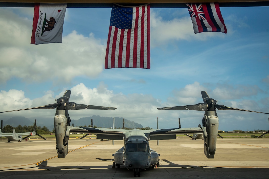 A static display of an MV-22B Osprey is showcased under the United States flag, flanked by the California and Hawaii state flags, symoblozing  Marine Tiltrotor Squadron 363's journey during the squadron's hangar dedication ceremony, Marine Corps Air Station Kaneohe Bay, Marine Corps Base Hawaii, Sept. 21, 2018. The dedication ceremony celebrated the arrival of Marines with VMM 363 and everyone that assisted in the construction of the hangar. The arrival of a second MV-22B Osprey squadron significantly increases Marine Aircraft Group 24's capability to respond to local emergencies within Hawaii and crises in the Indo-Pacific area of responsibility.