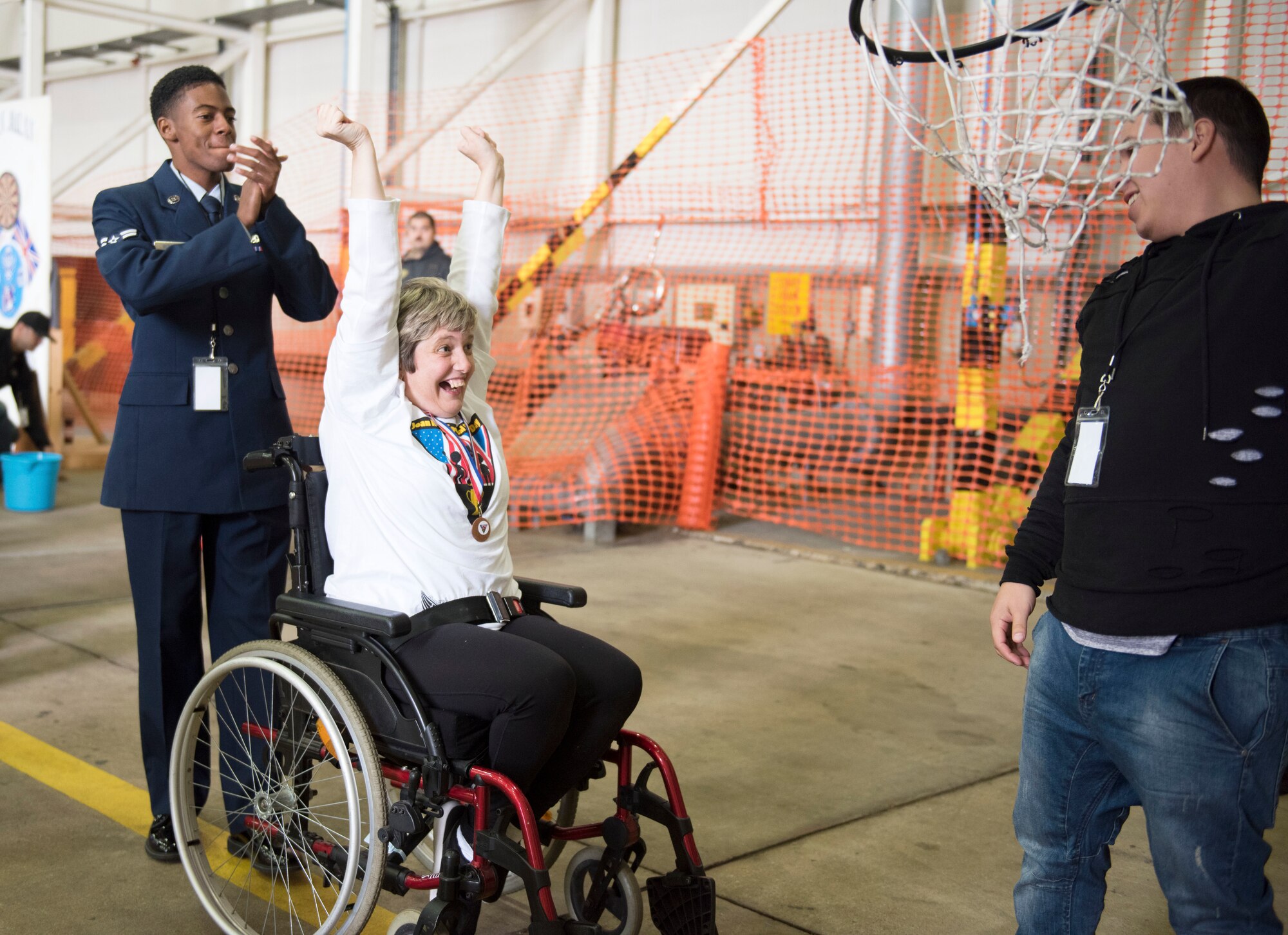 An athlete celebrates with her escort, Airman 1st Class Clarence Bennett, after getting a basketball in the hoop at the 37th Joan Mann Special Sports Day at RAF Mildenhall, England, Sept. 22, 2018.  Athletes from 28 local schools and organizations competed in 12 different sporting events, including the basketball shoot, wheel chair slalom, and American football throw. (U.S. Air Force photo by Senior Airman Lexie West)