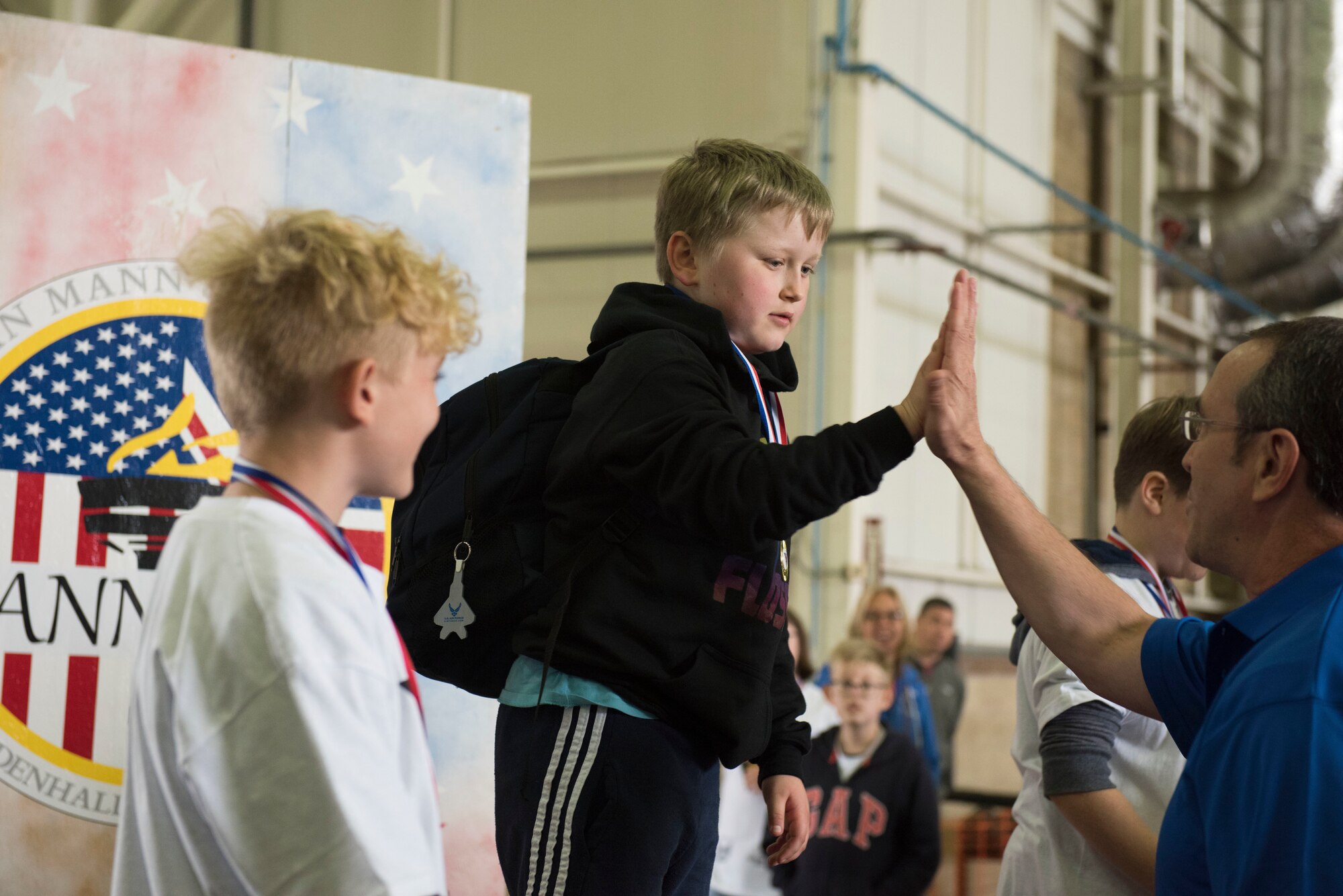 U.S. Air Force Chief Master Sgt. Clint Grizzell, 752nd Special Operations Group chief enlisted manager, high fives an athlete during the medal ceremony at the 37th Joan Mann Special Sports Day at RAF Mildenhall, England, Sept. 22, 2018.  Athletes from 28 local schools and organizations competed in 12 different sporting events, including the basketball shoot, obstacle course and football kick.  (U.S. Air Force photo by Senior Airman Lexie West)