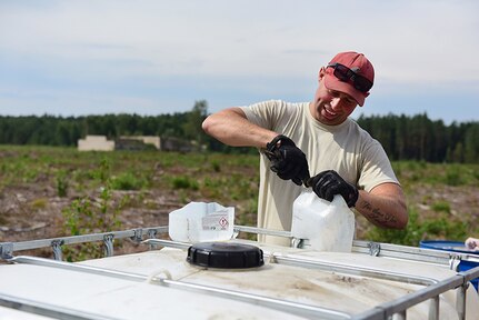 Tech. Sgt. Andrew Schmid, crew lead with the 201st Rapid Engineer Deployable Heavy Operational Repair Squadron Engineers, creates a make-shift funnel for adding hydraulic oil to equipment, Aug. 14, 2018. Schmidt is a team member of the third of four RED HORSE rotations traveling to Lithuania completing deployment for training by constructing a military air-to-ground training range to be used by NATO forces.