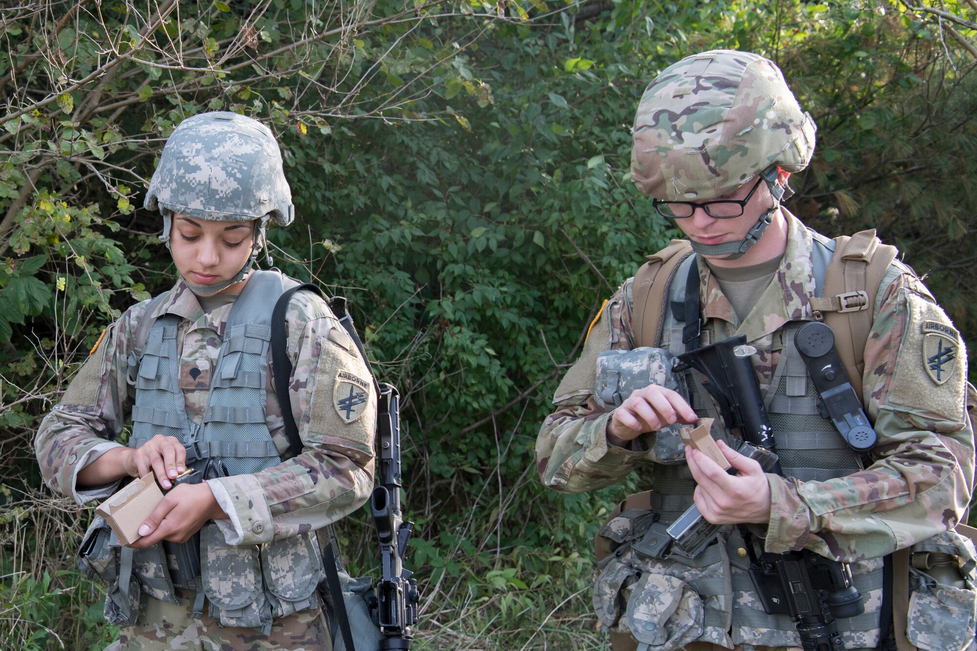 From the left, U.S. Army Spc. Kristen Bowman and Pfc. Jeff Hall, both 316th Psychological Operations Company PSYOP specialists, load ammunition prior to a react to contact exercise during an Army Warrior Task competition at Grissom Air Reserve Base, Indiana, Sept. 21, 2018. During the competition, Soldiers and Airmen worked together to test common combat skills in: hand grenade operations, weapons proficiency, map reading, moving under fire, escalation of force, evaluating and evacuating casualties and use of protective equipment. (U.S. Air Force photo by Tech. Sgt. Ben Mota)