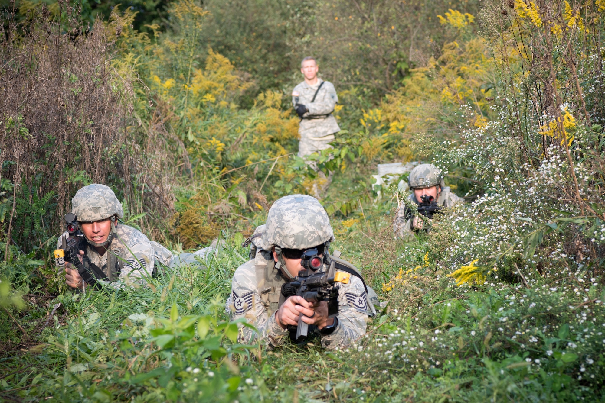 From the left, Staff Sgt. Adam Childers, Tech. Sgt. Christopher Barrett, and Staff Sgt. Bo Hall, all 434th Security Forces Squadron fire team members, react to contact while U. S. Army Staff Sgt. David Christopher, 316th Psychological Operations Company PSYOP specialist, scores their performance, during an Army Warrior Tasks competition at Grissom Air Reserve Base, Indiana, Sept. 21, 2018. Childers, Barett and Hall were one of twelve 3-man teams and the only Air Force team to participate in the competition developed to test combat skills. (U.S. Air Force photo by Tech. Sgt. Ben Mota)