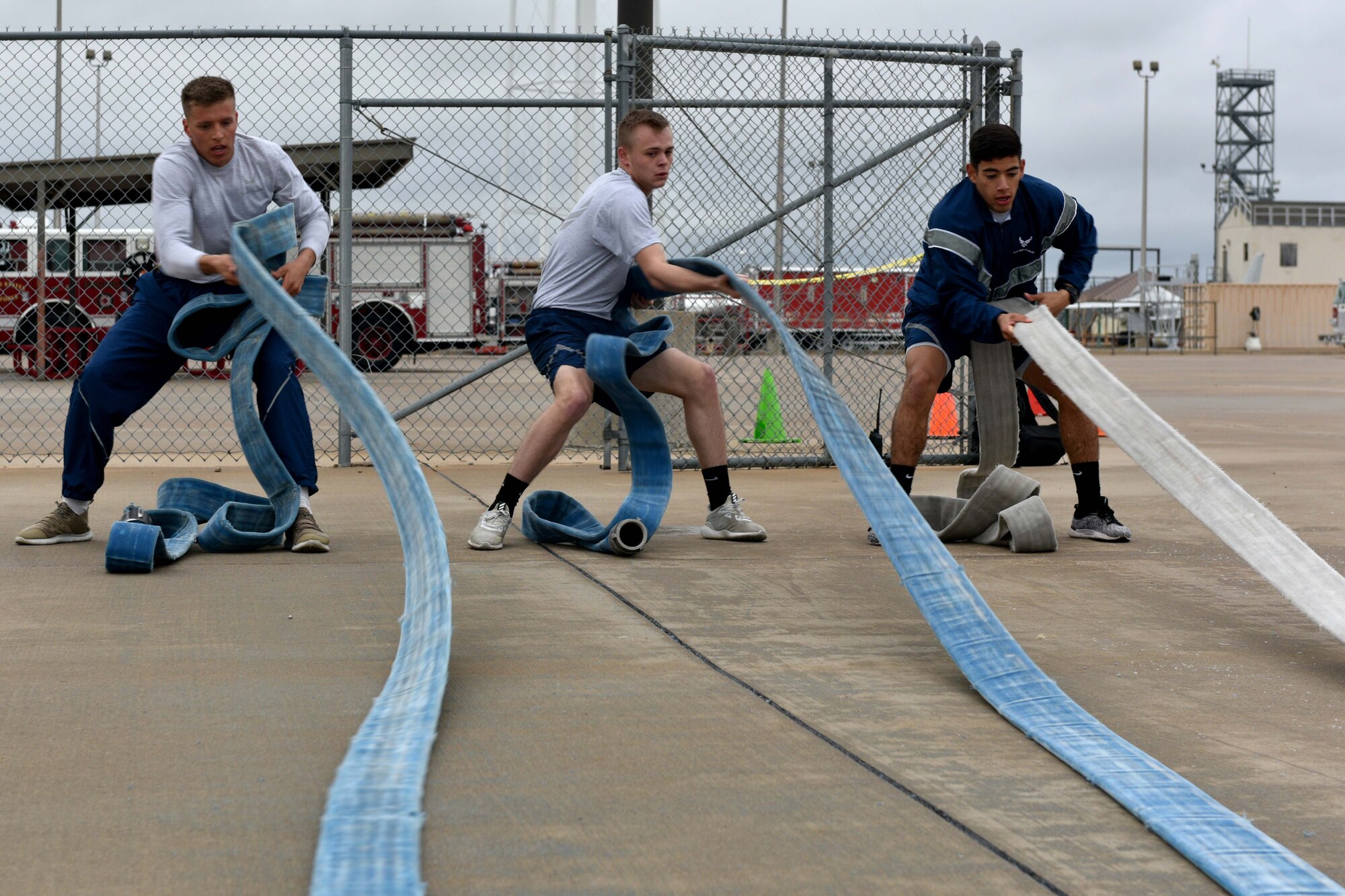 Airman 1st Class Garrett Rivett, Airman Haden Stoner and Airman Jake Peterson, 312th Training Squadron students, pull on fire hoses during the Blood, Sweat and Stairs competition at the Louis F. Garland Department of Defense Fire Academy on Goodfellow Air Force Base, Texas, Sept. 22, 2018. The competition used elements of the firefighter-training pad as exercises. (U.S. Air Force photo by Senior Airman Randall Moose/Released)