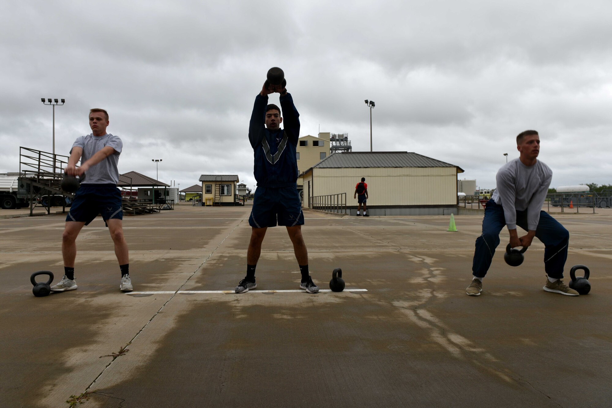 Airman Haden Stoner, Airman Jake Peterson and Airman 1st Class Garrett Rivett, 312th Training Squadron students, lift kettlebells during the Blood, Sweat and Stairs competition at the Louis F. Garland Department of Defense Fire Academy on Goodfellow Air Force Base, Texas, Sept. 22, 2018. Participants would lift the weights 40 times then carry them 20 yards. (U.S. Air Force photo by Senior Airman Randall Moose/Released)