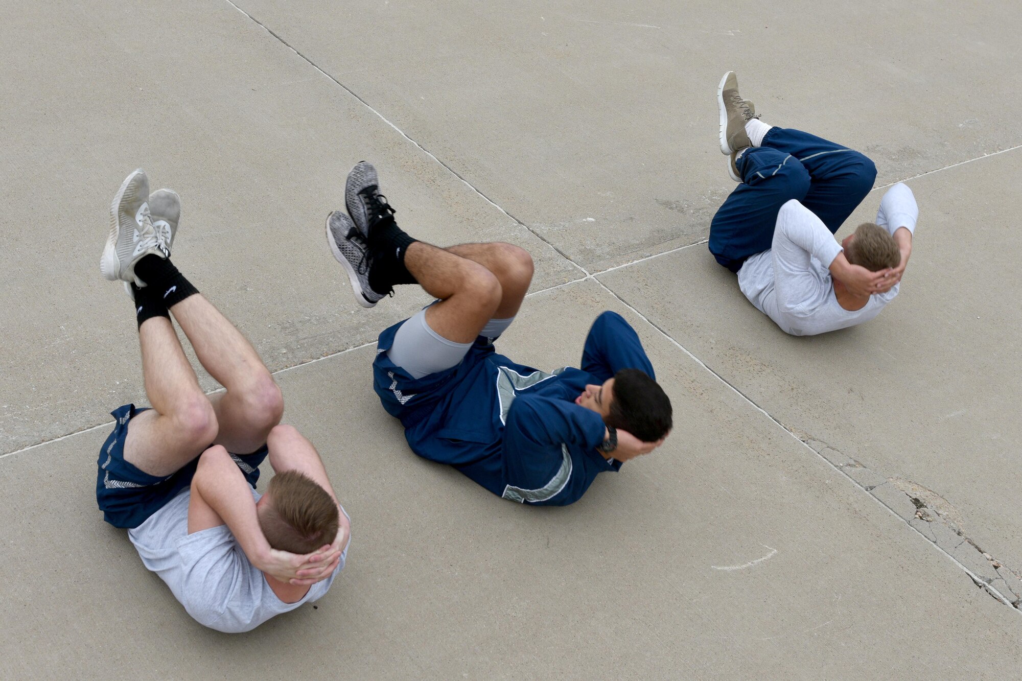 Airman Haden Stoner, Airman Jake Peterson and Airman 1st Class Garrett Rivett, 312th Training Squadron students, perform crunches during the Blood, Sweat and Stairs competition at the Louis F. Garland Department of Defense Fire Academy on Goodfellow Air Force Base, Texas, Sept. 22, 2018. Competitors ran the nearly 2-mile course with multiple stops to complete exercises such as jumping jacks, burpees and jump-squats. (U.S. Air Force photo by Senior Airman Randall Moose/Released)