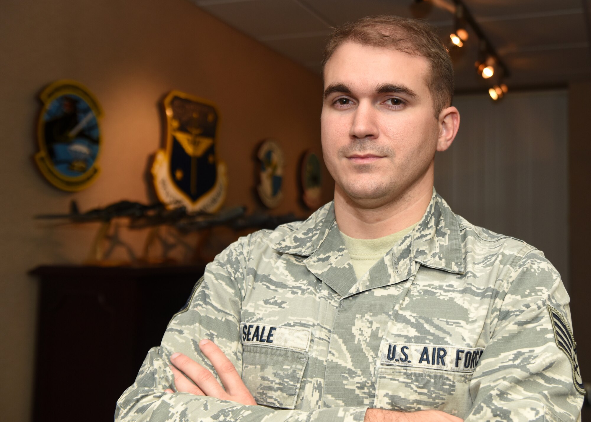 A man in uniform stands in front of a wall with plaques.