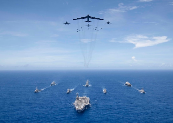 The aircraft carrier USS Ronald Reagan (CVN 76), foreground, leads a formation of Carrier Strike Group Five ships as Air Force B-52 Stratofortress aircraft and Navy F/A-18 Hornet aircraft pass overhead for a photo exercise during Valiant Shield 2018 in the Philippine Sea Sept. 17, 2018. The biennial, U.S. only, field-training exercise focuses on integration of joint training among the U.S. Navy, Air Force and Marine Corps. This is the seventh exercise in the Valiant Shield series that began in 2006. (U.S. Navy photo by Mass Communication Specialist 3rd Class Erwin Miciano)