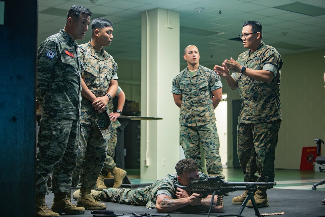 CAMP KINSER, Okinawa, Japan - Sgt. Maj. Jong Ik Jun, sergeant major of the Republic of Korea Marine Corps (far left) receives a brief on the Indoor Simulated Marksmanship Trainer (ISMT) program from Staff Sgt. Ryan W. Betonie (right), a marksmanship instructor for 3rd Marine Logistics Group, here, 20 Sept. Jun’s visit to 3rd MLG is the first time the R.O.K. Marine Corps sergeant major has visited III Marine Expeditionary Force Units at their home station.  Republic of Korea and United States Marine Corps forces are committed to the ironclad ROK-U.S. alliance and work together to further develop their partnership and combined capabilities. (U.S. Marine Corps photo by Lance Cpl. Armando Elizalde)