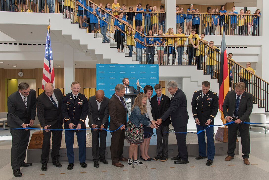 A group of people cut a blue ribbon.