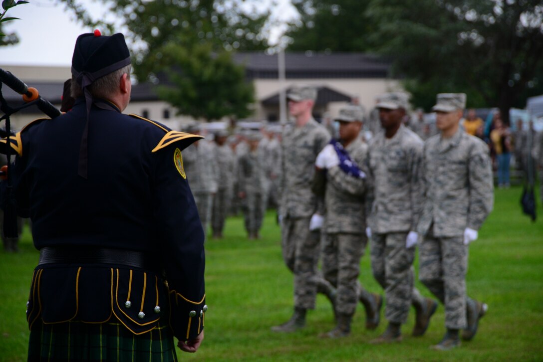 A ceremonial bagpiper watches Dover Air Force Base Honor Guard members carry a folded American flag during a POW/MIA retreat ceremony Sept. 21, 2018, at Dover Air Force Base, Del. Bagpipers traditionally play "Scotland the Brave" or "Amazing Grace" during military ceremonies. (U.S. Air Force photo by Airman 1st Class Jonathan W. Harding)