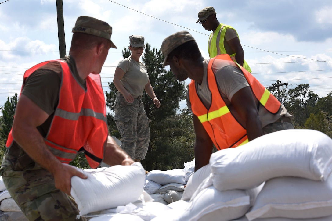 Soldiers stack sandbags to reinforce a flood barrier along Highway 501 to ensure the roadways remains passable.