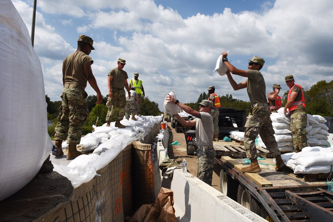 Soldiers stack sandbags to reinforce a flood barrier along Highway 501 to ensure the roadways remains passable.