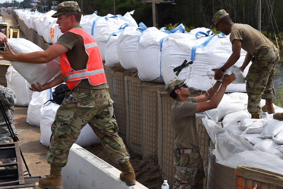 Soldiers reinforce a flood barrier along Highway 501 to ensure the roadway remains passable.