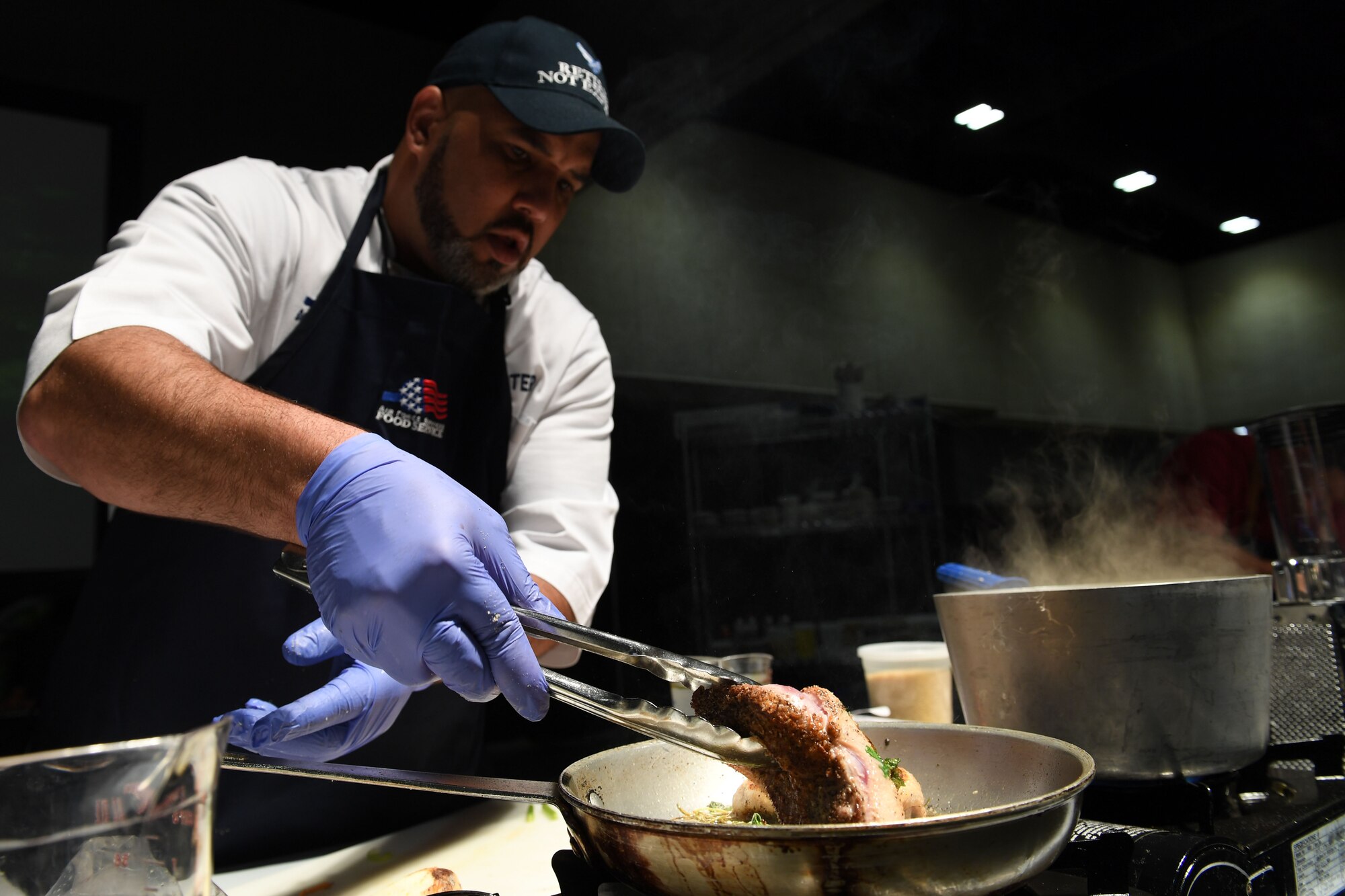 A man flips duck breast cooking in a pan.