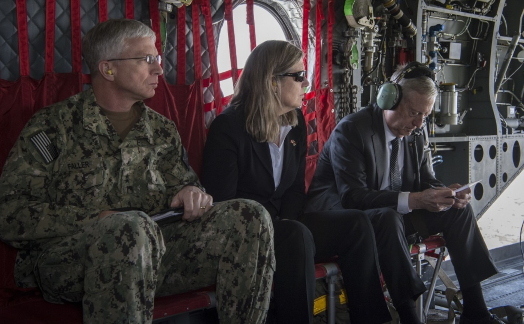 Admiral, civilian assistant and secretary of defense travel on a helicopter.