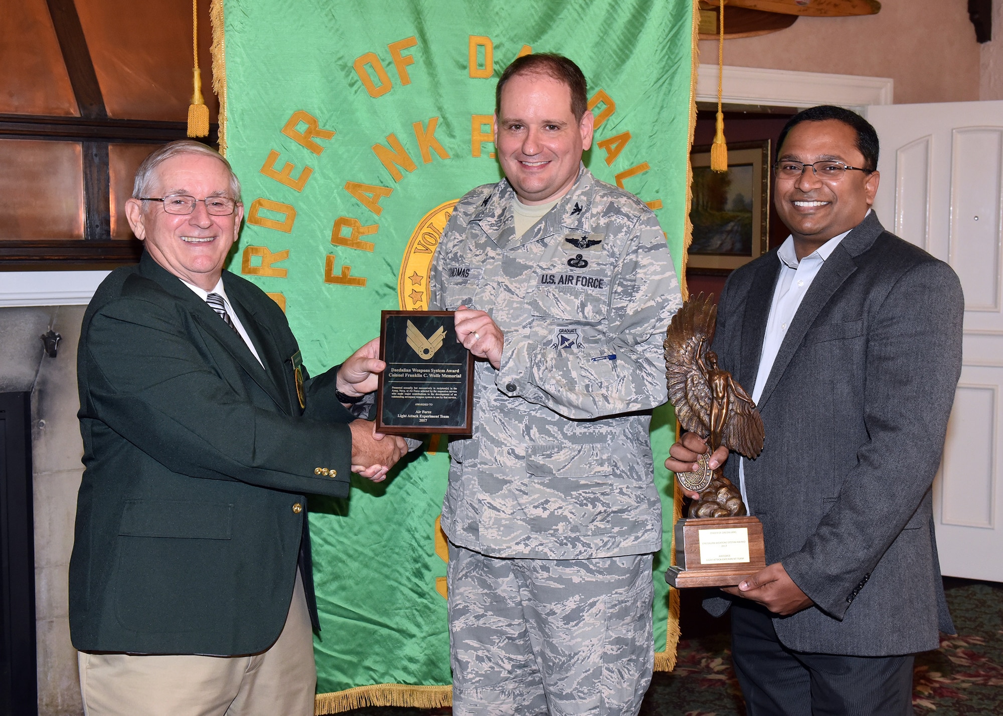 Jim DeStout, left, Adjutant, Flight 9 – Frank P. Lahm Order of Daedailians, presents the 2017 Daedalian Colonel Franklin C. Wolfe Weapon Systems Award plaque to Col. Anthony Thomas, Air Force Life Cycle Management Center advisor to the Light Attack Experiment Phase 1 team, and trophy to Dr. Ravi Penmetsa, Light Attack Experiment Team Lead Sept. 20, 2018. The combined efforts of personnel from the Air Force Life Cycle Management Center and Air Force Research Laboratory contributed to the overall success of the Phase I Experiment effort, which, in turn, paved the way for the Phase II Experiment in 2018 and the further development and maturation of the USAF Light Attack Aircraft acquisition strategy. (U.S. Air Force photo/Al Bright)