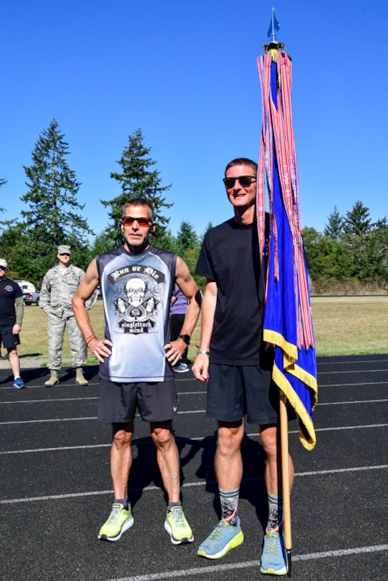 Bruce Robie, left, 225th Support Squadron National Airspace System Defense program manager, and 1st Lt. Krosby Keller, right, 225th Air Defense Squadron air battle manager, proudly hold the Western Air Defense Sector colors after completing 174 miles between them during the Joint Base Lewis-McChord 24-Hour POW/MIA Remembrance Run Sept. 19, 2018.  Keller placed first in individual standings with 100 miles and Robie finished second with 74 miles. (U.S. Air National Guard photo by Maj. Kimberly Burke)