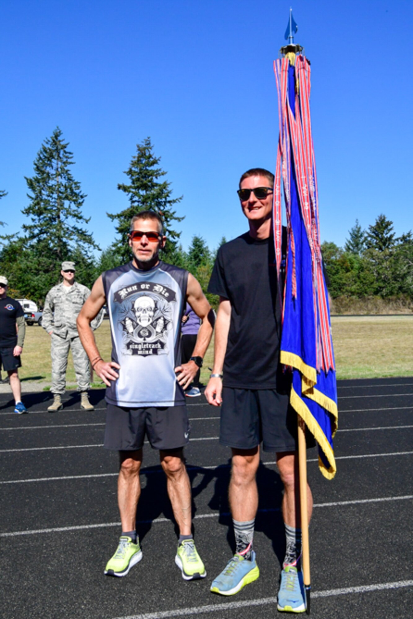 Bruce Robie, left, 225th Support Squadron National Airspace System Defense program manager, and 1st Lt. Krosby Keller, right, 225th Air Defense Squadron air battle manager, proudly hold the Western Air Defense Sector colors after completing 174 miles between them during the Joint Base Lewis-McChord 24-Hour POW/MIA Remembrance Run Sept. 19, 2018.  Keller placed first in individual standings with 100 miles and Robie finished second with 74 miles. (U.S. Air National Guard photo by Maj. Kimberly Burke)
