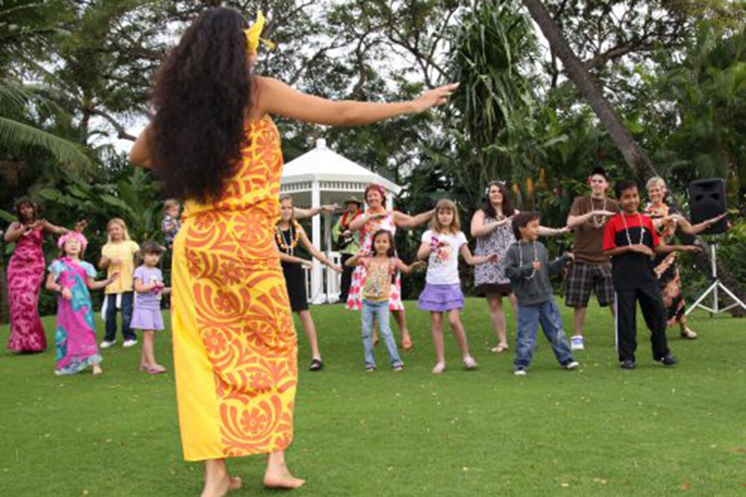 A woman shows people how to do the hula.