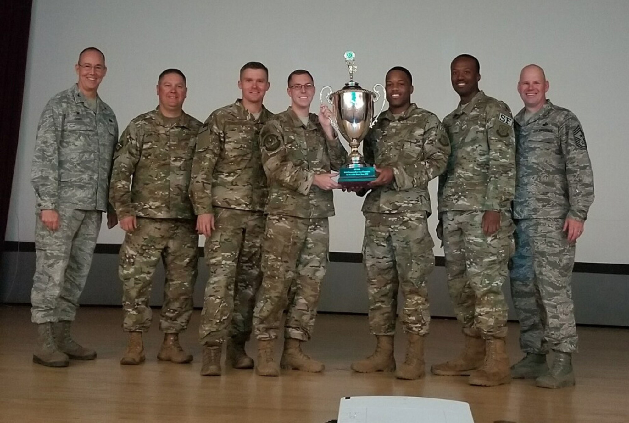 Members of the of the 377th Security Forces Squadron hoist the 2017-18 intramural sports season's Commander's Cup trophy Sept. 24, 2018, here. They are flanked by 377th Air Base Wing Commander Col. Richard Gibbs (left) and 377th Command Chief Master Sgt. Robert Stamper (right). The pair presented the trophy. (U.S. Air Force photo by Joanne Perkins)