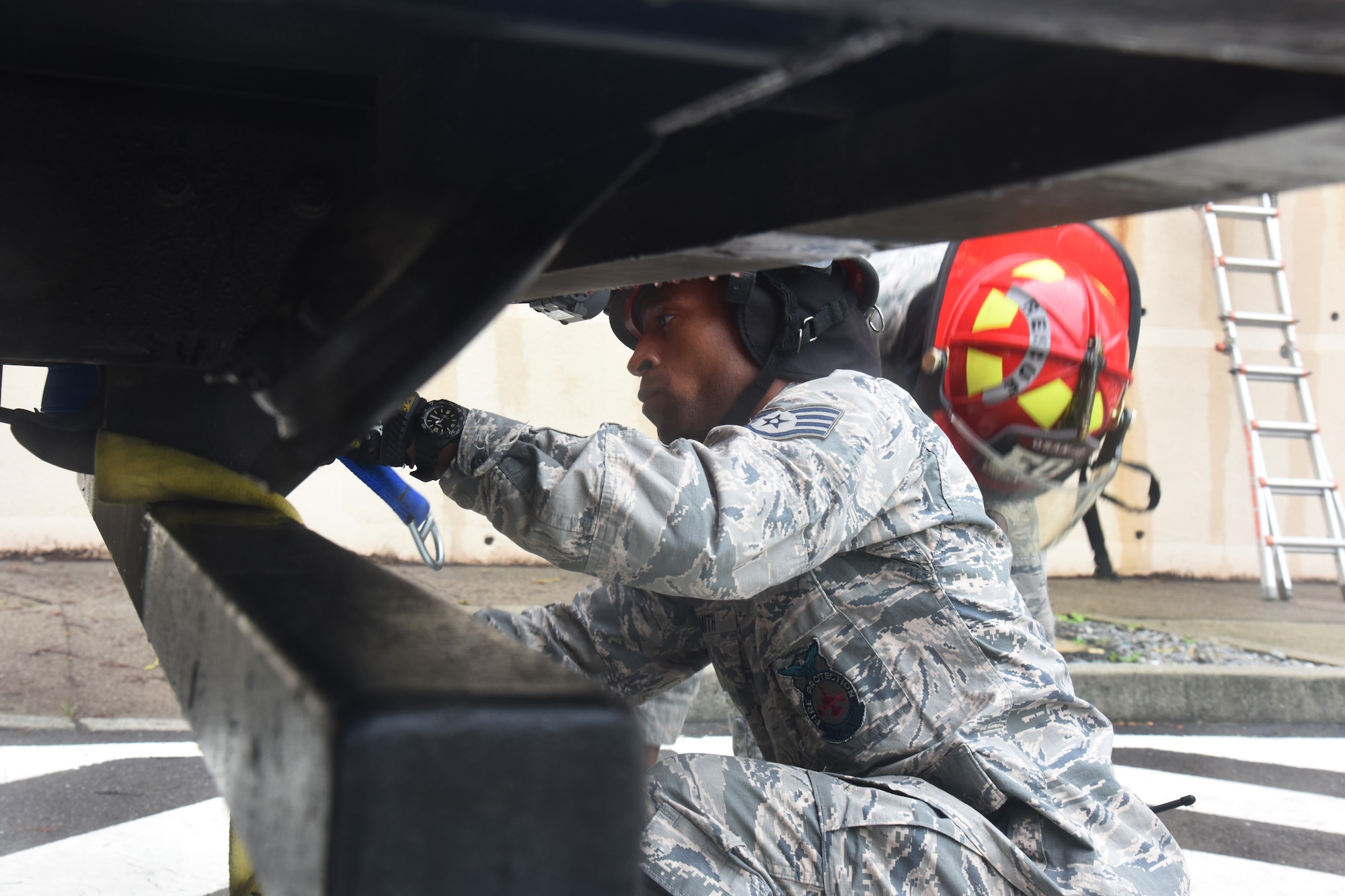 U.S Staff Sgt. Devon Smith, firefighter with the 51st Civil Engineer Squadron fire department, wraps a cord around the edge of a fire truck during a mass casualty exercise at Osan Air Base, Republic of Korea, Sept. 20, 2018. The firefighters used the cord to raise and lower a stretcher to rescue a simulated victim out of a burining building. (U.S. Air Force photo by Tech. Sgt. Ashley Tyler)