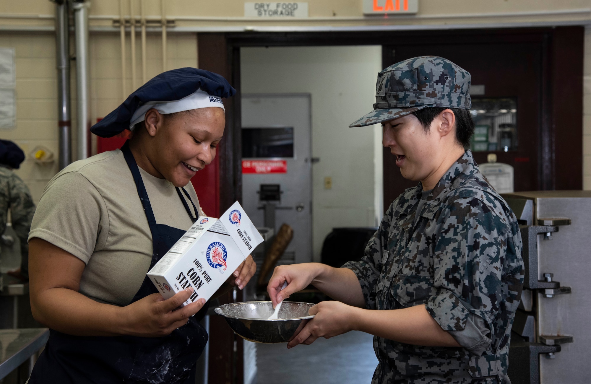 U.S. Air Force Airman 1st Class Ty’Lacia Berard, a 35th Force Support Squadron food specialist, helps Japan Air Self-Defense Force Tech. Sgt. Tomoyo Kato, a 27th Aircraft Control and Warning Squadron nutritionist, create a corn starch mix during a Bilateral Exchange Program visit at Misawa Air Base, Japan, Sept. 21, 2018. Kato learned how to make larger portions of meals for thousands of Airmen, whereas she normally only makes meals for approximately 300 personnel at her unit. (U.S. Air Force  photo by Senior Airman Sadie Colbert)