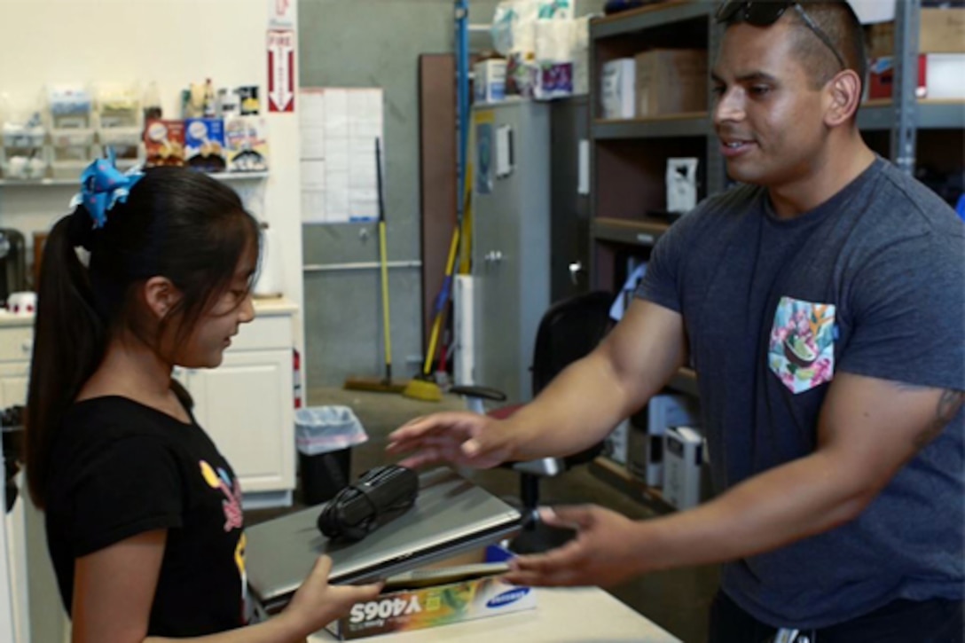 A sailor helps a woman with her computer.