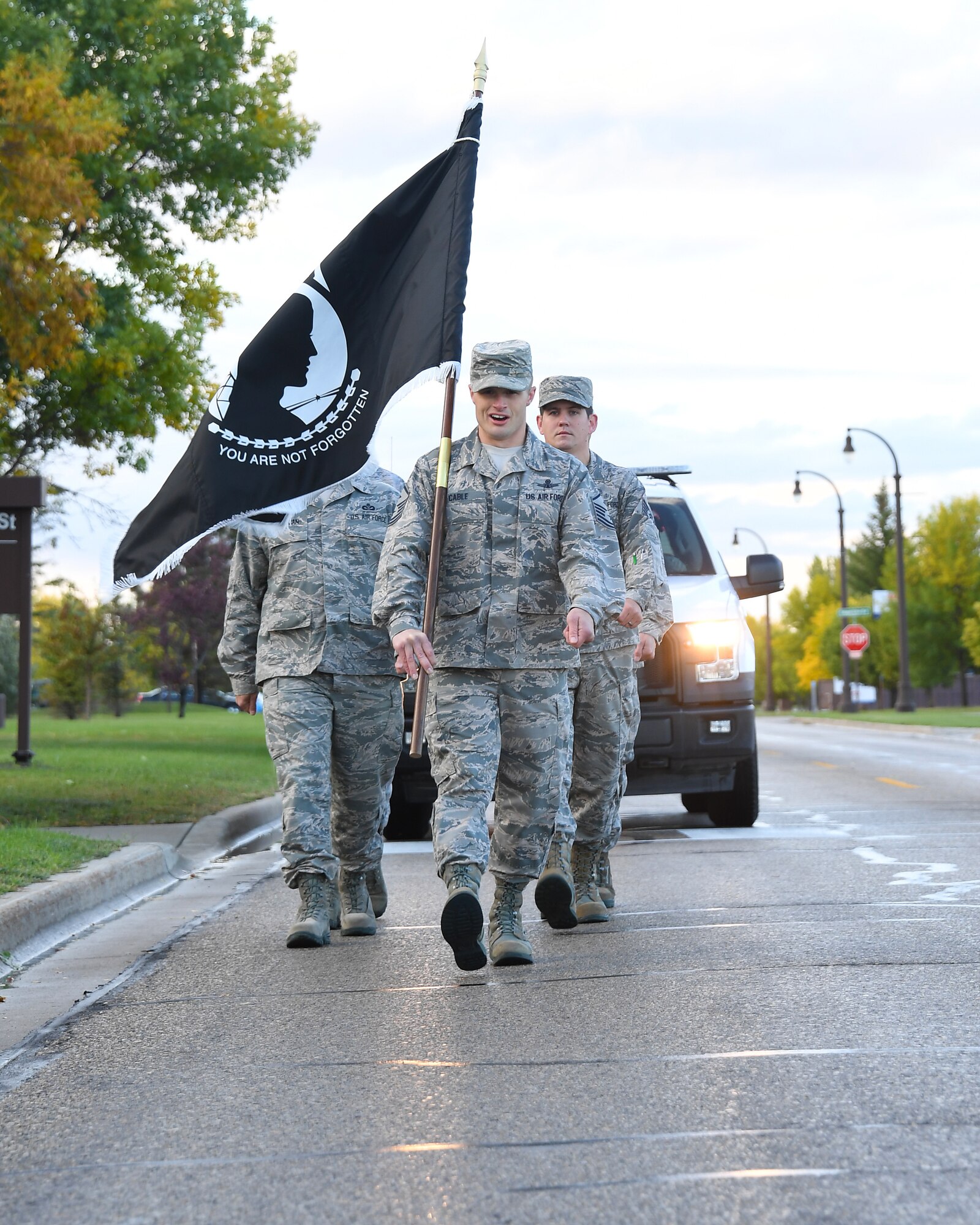 Master Sgt. Daniel Cable, 319th Operations Support Squadron fire sergeant, center, calls cadence as he leads an element to the base honor guard building for a POW/MIA ceremony September 21, 2018, on Grand Forks Air Force Base, North Dakota. Prior to the ceremony, the POW/MIA flag was kept in motion by base Airmen who carried it during a 24-hour run. (U.S. Air Force photo by Airman 1st Class Elora J. Martinez)
