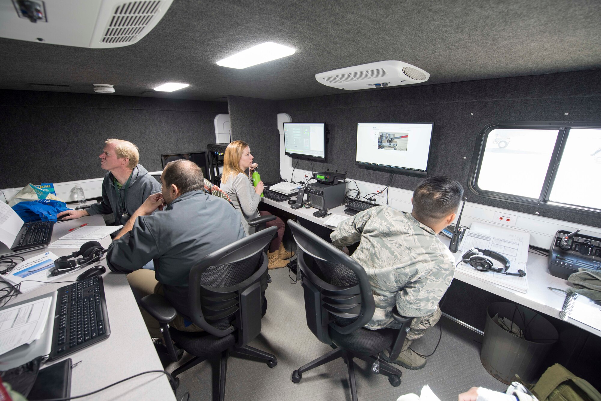 Members from engineering and technical support company JT4 and the 418th Flight Test Squadron sit in the mobile control room of the newly created Receiver Simulation Tool. This is where aerial refueling simulation tests are monitored and recorded. The RST is a ground-based system designed to simulate events that happen during aerial refueling between receiver aircraft and new tankers such as the KC-46 Pegasus, Australian KC-30 and Italian 767. (U.S. Air Force photo by Brad White)