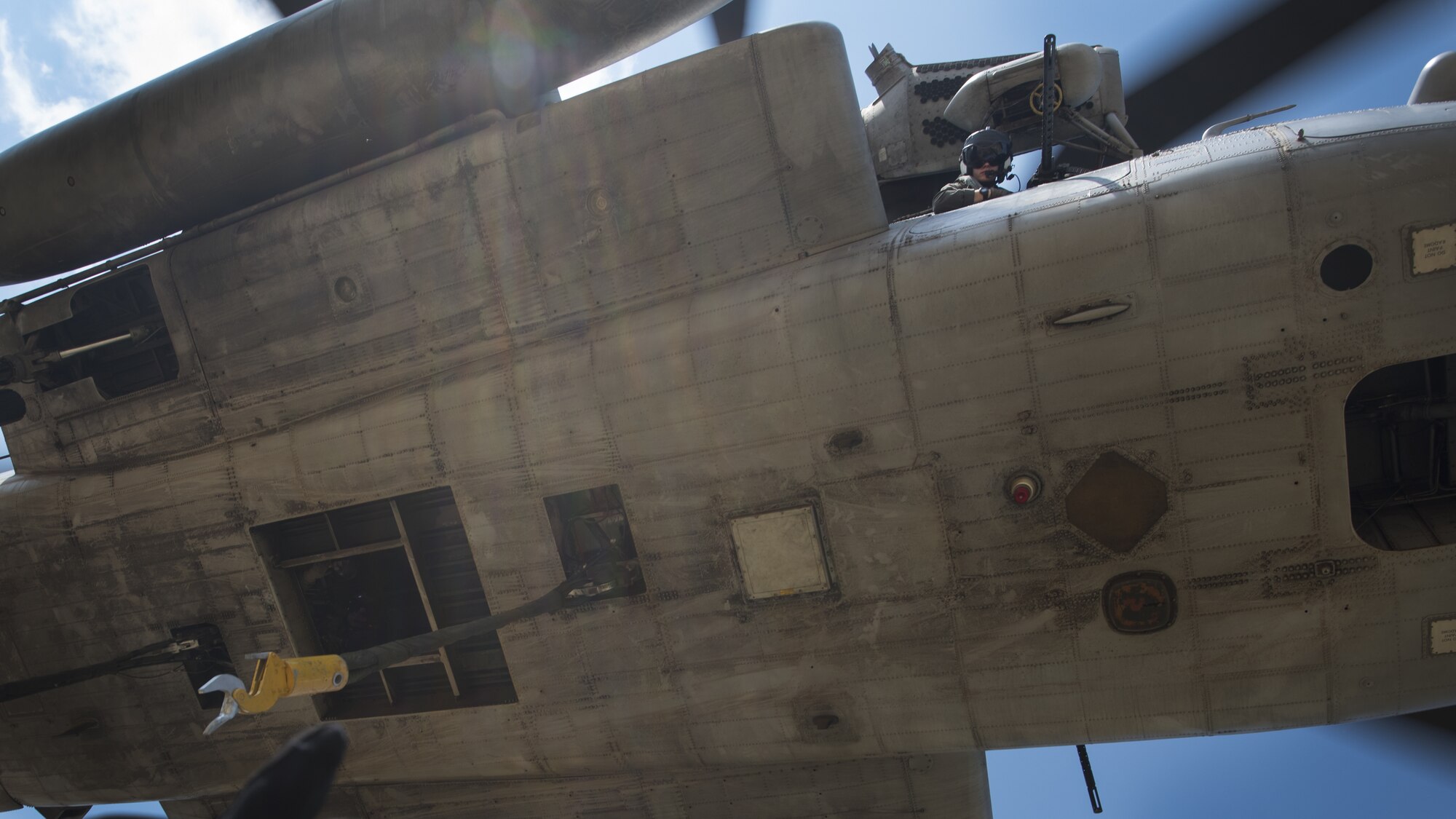 A Marine Heavy Helicopter Squadron 772 (HMH-772) crew chief looks out a window of a CH-53E Super Stallion near Joint Base McGuire-Dix-Lakehurst, New Jersey, Sept. 6, 2018. The Marine guided the pilot to align the CH-53E over a Humvee before connecting them with hooks to lift it off the ground. (U.S. Air Force photo by Airman Ariel Owings)