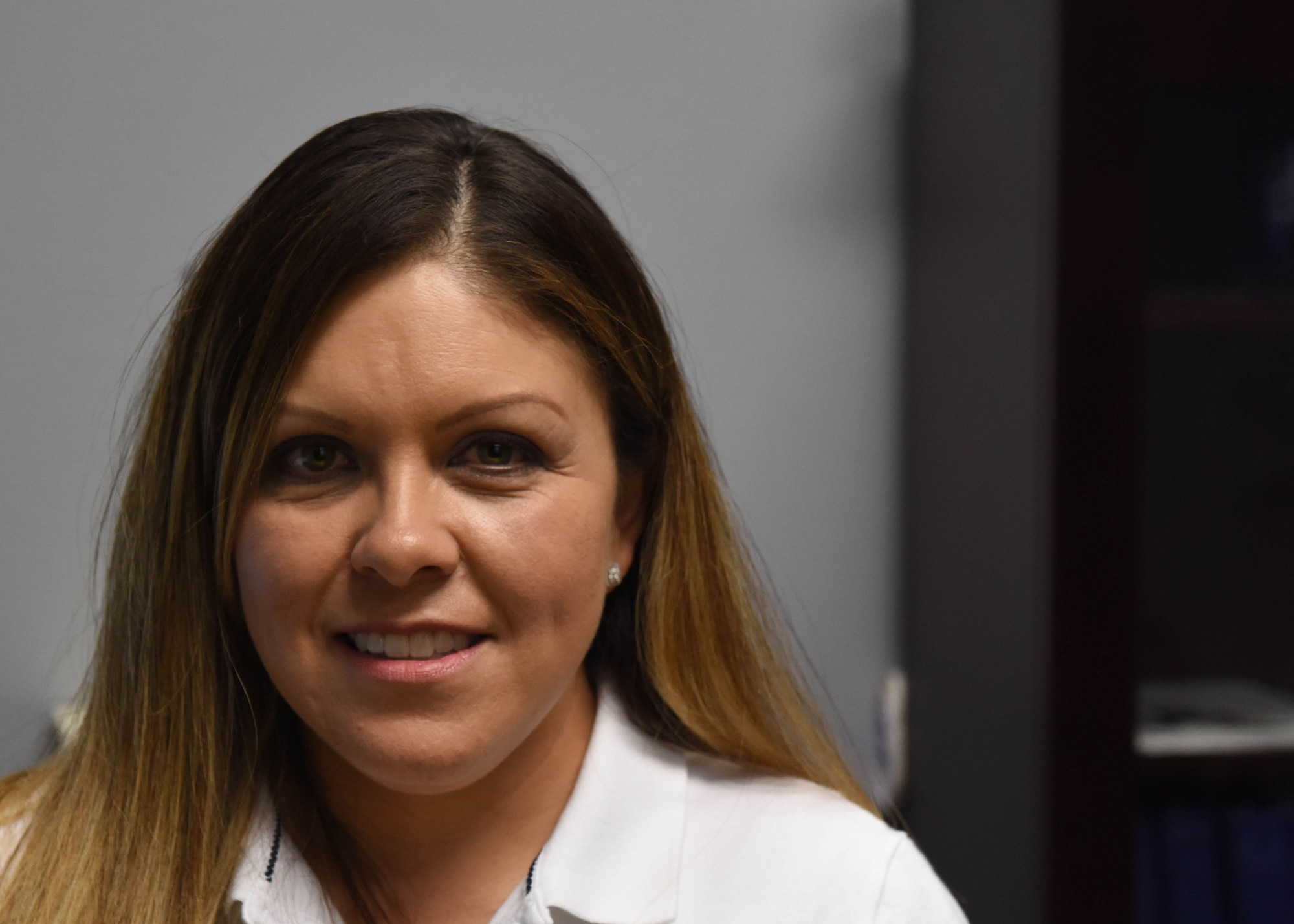 Marcia Sanchez, executive officer of the 97th Maintenance Group, stands behind her desk, Sept. 18, 2018, at Altus Air Force Base, Okla. Sanchez is proud to be the first woman in her family to earn a master’s degree. (U.S. Air Force photo by Dallin Wrye)