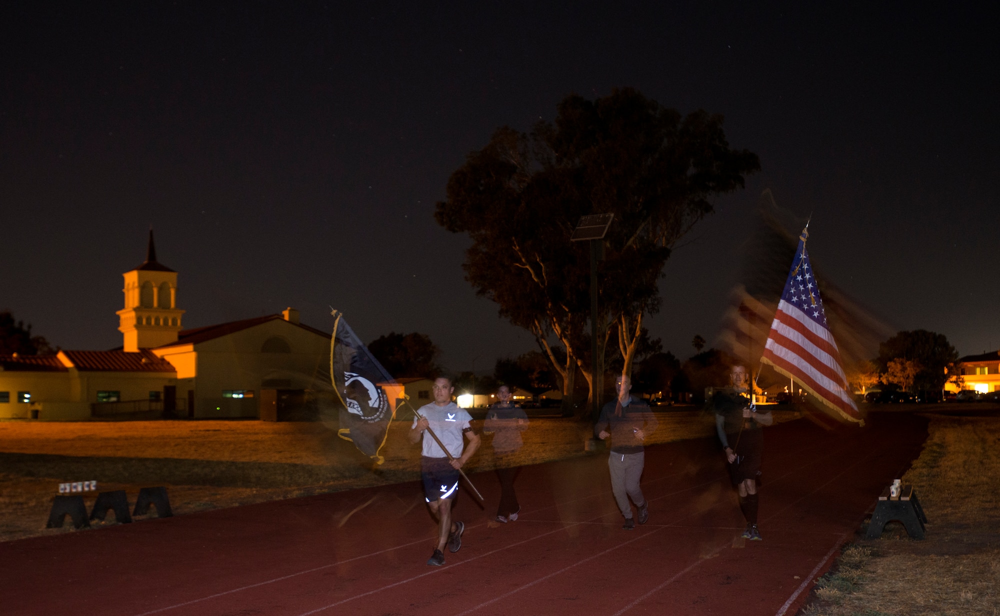 Members of the 349th Air Mobility Wing carry the American Flag and POW/MIA flag during the POW/MIA Recognition Day ceremony run at Travis Air Force Base, Calif., on Sept. 21, 2018. Team Travis Airmen kept the flag in constant motion for 24 hours straight in honor of American prisoners of war and those missing in action.