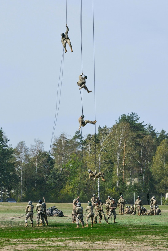 Soldiers slide down their ropes while rappelling from a UH-60M Black Hawk helicopter.