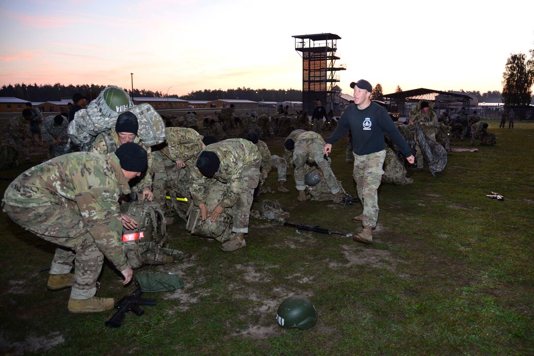 An Army air assault instructor yells to students to recover their field equipment after being inspected.