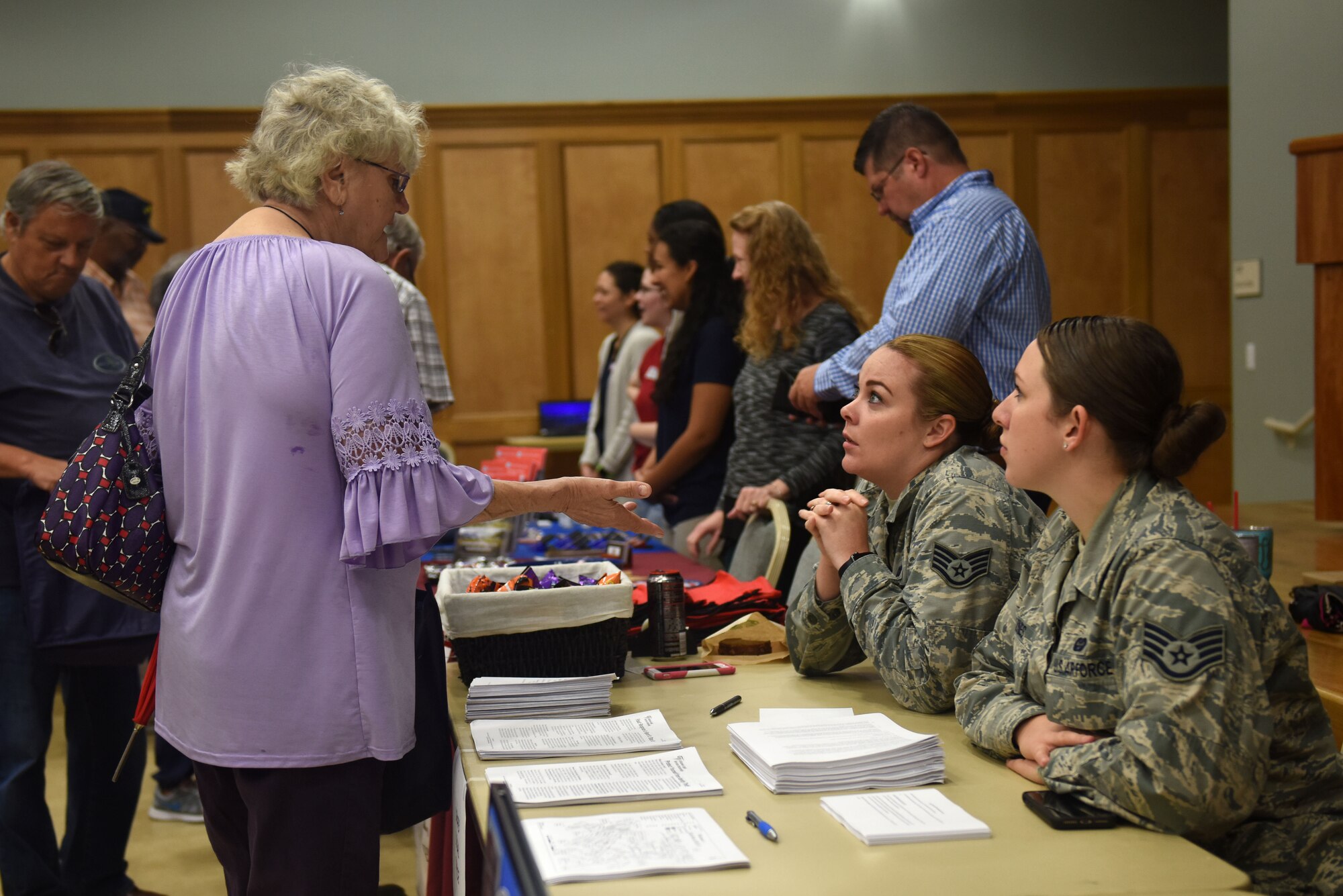 A woman in a purple blouse talks to two women in the Airman Battle Uniform.