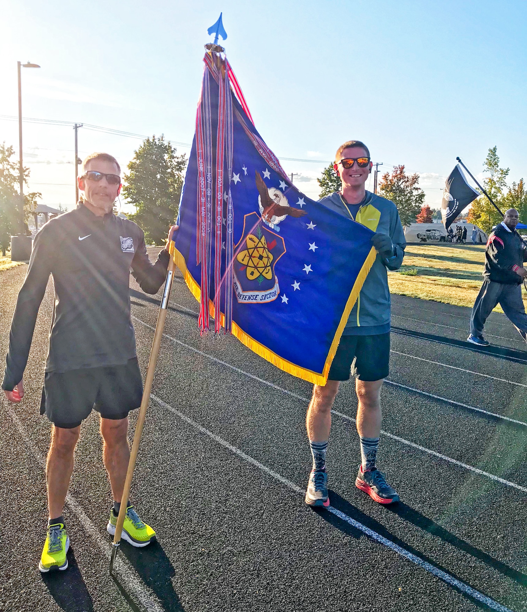 Bruce Robie, left, 225th Support Squadron National Airspace System Defense program manager, and 1st Lt. Krosby Keller, right, 225th Air Defense Squadron air battle manager, proudly hold the Western Air Defense Sector colors after completing 174 miles between them during the Joint Base Lewis-McChord 24-Hour POW/MIA Remembrance Run Sept. 19, 2018.  Keller placed first in individual standings with 100 miles and Robie finished second with 74 miles. (Courtesy photo)