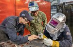 HT1 Mitchell Hovland, left, works with trainees HT2 Dustin Harley, middle and HT3 Brandon Orozco, on a test weld at the Puget Sound Naval Shipyard & Intermediate Maintenance Facility Everett Detachment.