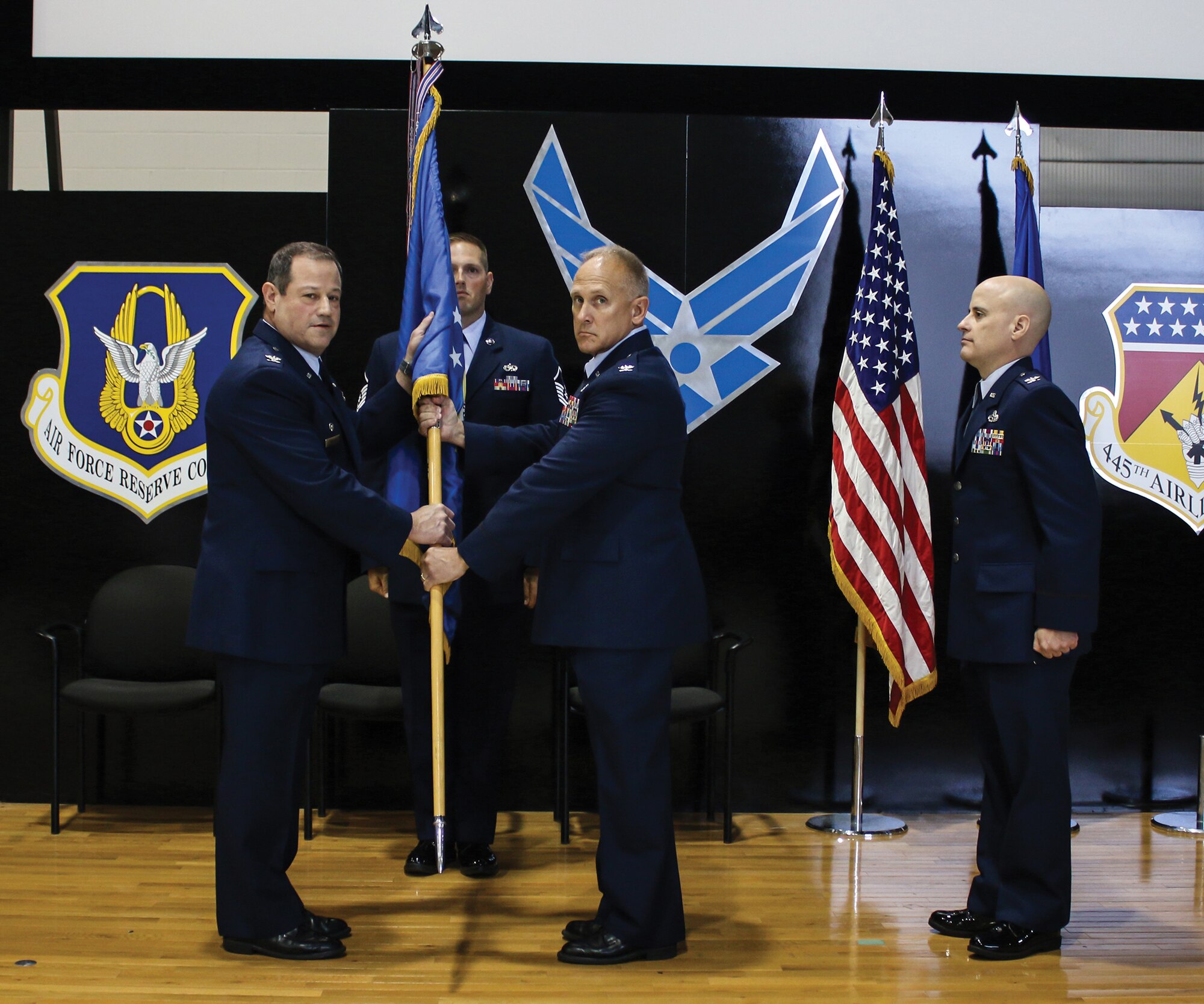 Col. Adam Willis, 445th Airlift Wing commander, passes the guidon to Col. Jay Smeltzer, incoming 445th Maintenance Group commander, as Col. Cade Gibson, outgoing MXG commander and Master Sgt. David Griffith, MXG first sergeant, stand at attention during the 445th MXG change of command ceremony Sept. 9, 2018