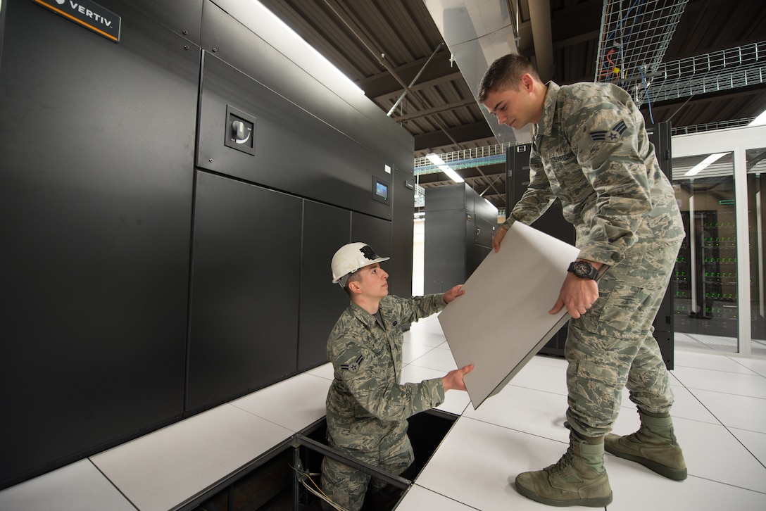 Senior Airman Mario Lunato, 2nd System Operations Squadron system (SYOS) administrator and Airman 1st Class Caleb Childers, 2nd SYOS cyber surety technician, replace a flooring panel next to a computer room air conditioner (CRAC) in the 557th Weather Wing’s High Performance Computer Data Center at Offutt Air Force Base, Nebraska, April 27, 2018. The CRACs were replaced as part of a $4 million plan to improve the data center’s cooling capabilities. (U.S. Air Force photo by Paul Shirk)