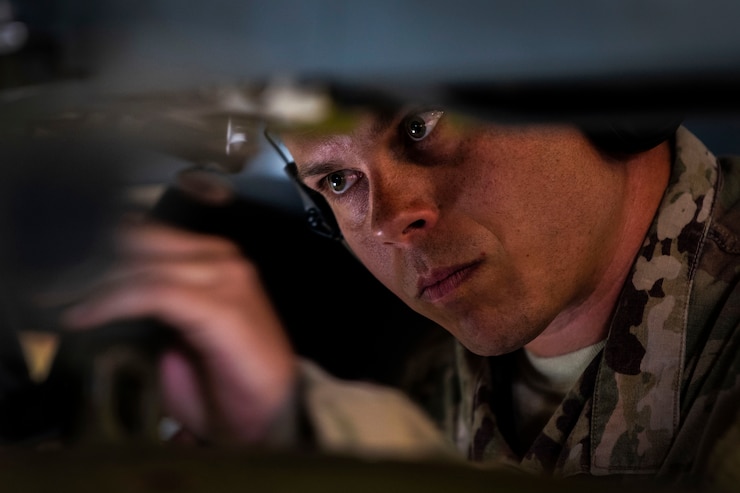 An Airman looks intently as he fixes a part of an aircraft