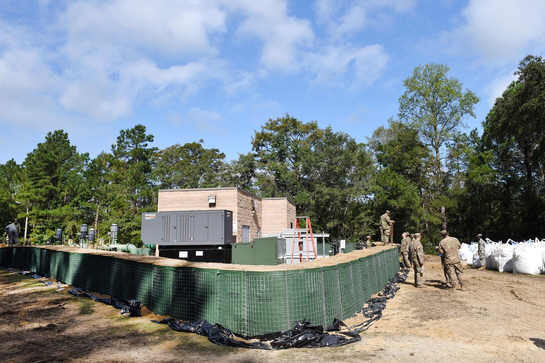 Soldiers work together to build flood water abatement barriers.