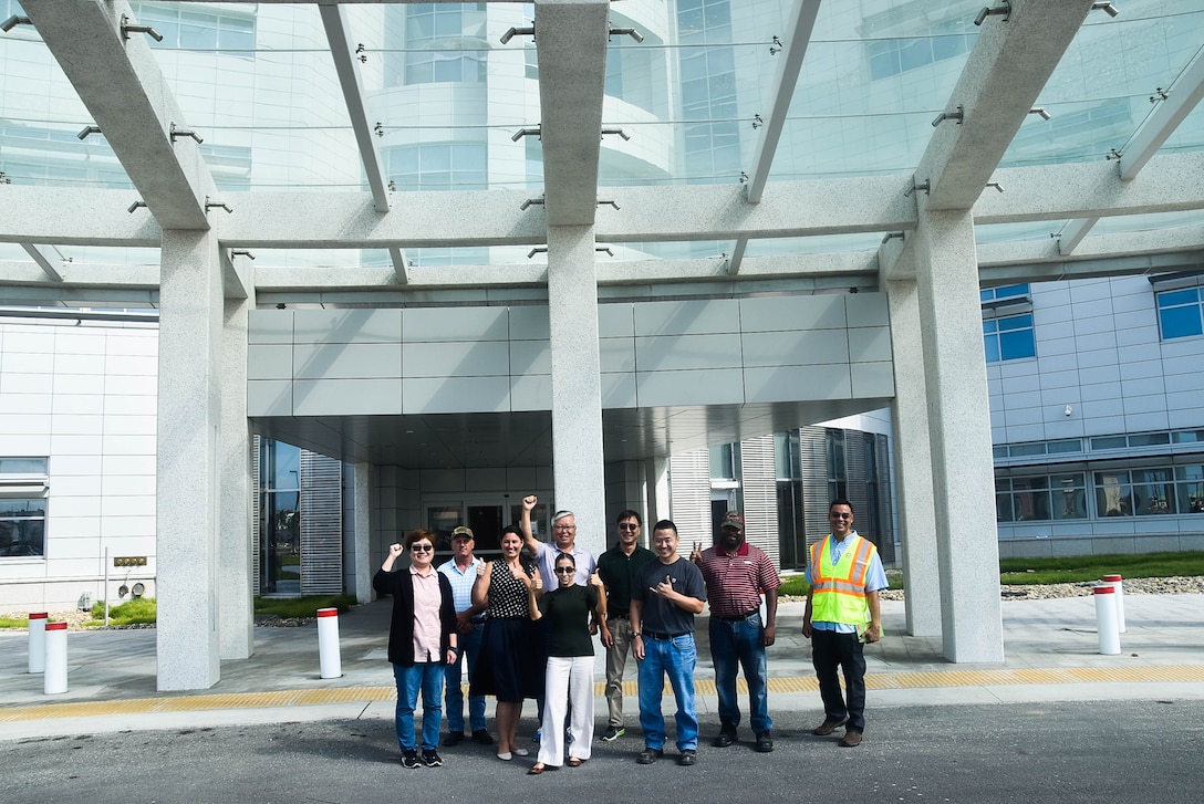 Elisa Beck (center), Resident Engineer, Medical Resident Engineer, stands with her team in front of the new Brian Allgood Army Community Hospital, Camp Humphreys, South Korea, Sep. 7.