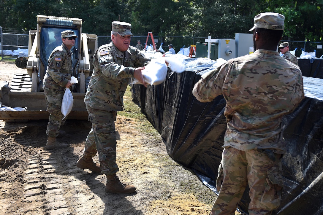 Army Brig. Gen. Jeff Jones, deputy adjutant general of South Carolina’s National Guard, tosses sandbags to a soldier.