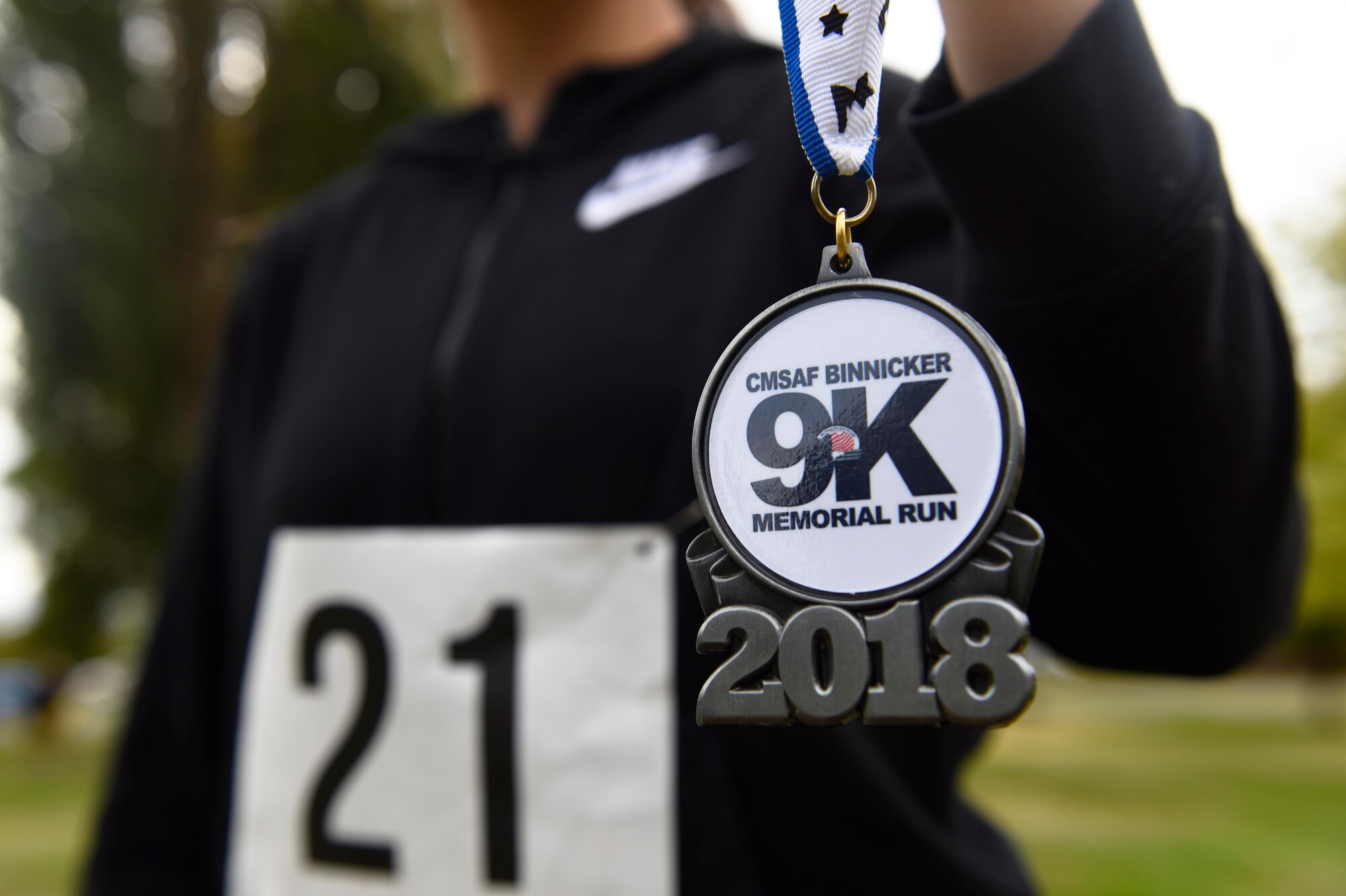 A participant holds up a finisher's medallion after running the CMSAF Binnicker 9K Memorial Run Sept. 22, 2018, at Miller Park in Fairchild Air Force Base, Washington. (U.S. Air Force photo/Airman 1st Class Lawrence Sena)