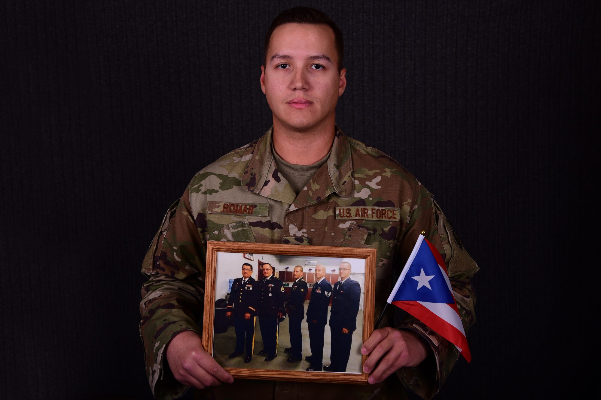 U.S. Air Force 1st Lt. Jorge Roman-Castillo, 386th Air Expeditionary Wing Sexual Assault Response Coordinator, poses with a photo of his family Sept. 27, 2018, at an undisclosed location in Southwest Asia. Roman-Castillo, a fourth-generation veteran, said his upbringing of respect has proved critical to his effectiveness as a SARC and an Air Force officer. (U.S. Air Force photo by Staff Sgt. Christopher Stoltz)