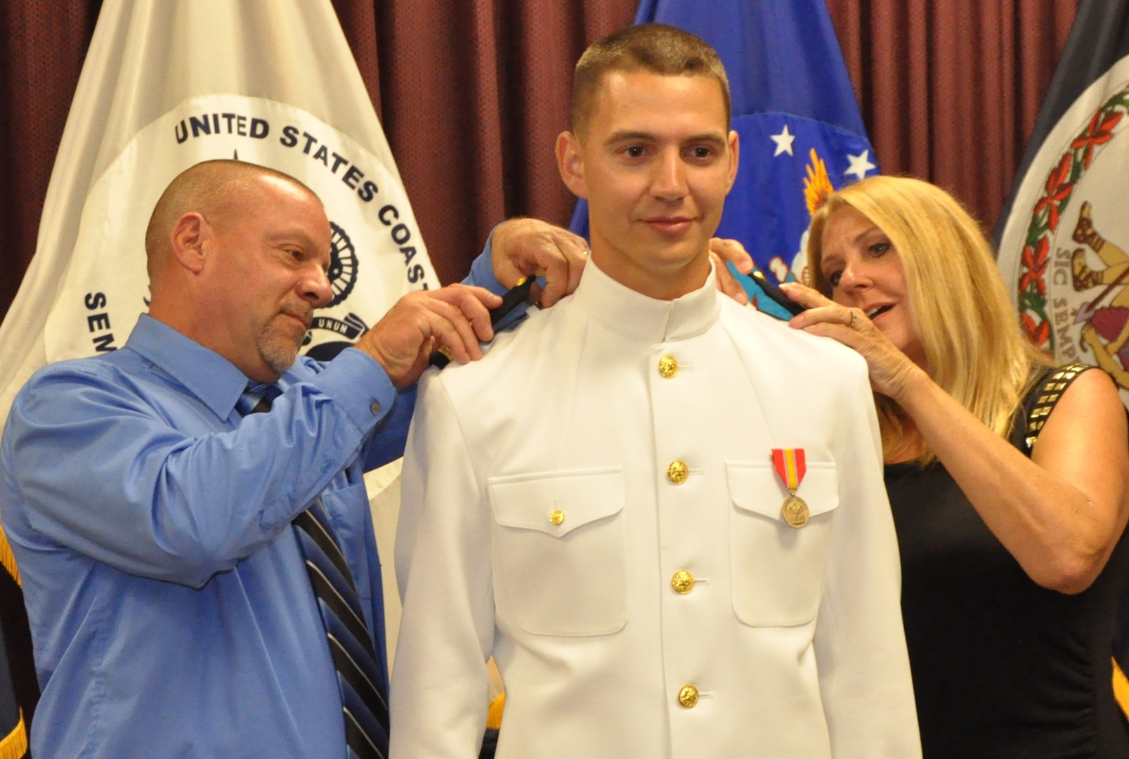 IMAGE: DAHLGREN, Va. (Sept. 11, 2018) – U.S. Navy Ensign Dillard Patton’s parents, Dale and Sharon, place officer shoulder boards on their son’s uniform at his commissioning ceremony held at the Aegis Training and Readiness Center. The NSWC Dahlgren Division System Safety Engineering Division civilian engineer was commissioned into the officer ranks of the Naval reserves through the Direct Commission Officer program. The newly commissioned officer expressed a special appreciation to his family during the ceremony. “Without your support, I wouldn’t be standing where I am today,” said Patton. “You have stood by my side through my best and my worst, but in all instances you motivated me to give it my all and succeed.”