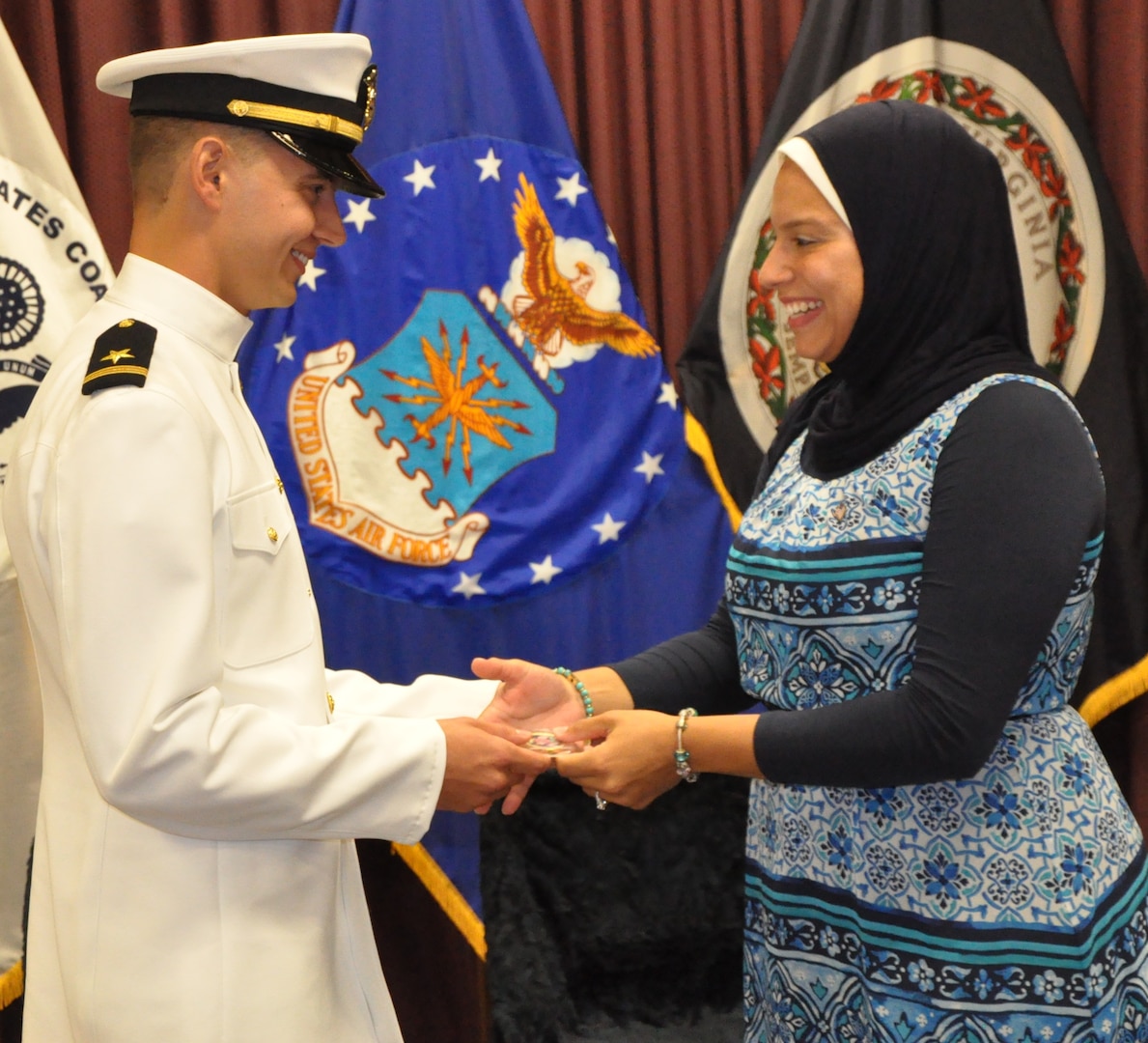 IMAGE: DAHLGREN, Va. (Sept. 11, 2018) – U.S. Navy Ensign Dillard Patton presents a Navy spouse coin to his wife, Nourhan Ibrahim, moments after he was commissioned into the Naval reserves as an ensign. The NSWCDD System Safety Engineering Division civilian engineer expressed a special appreciation to his wife, son, and all his family during the ceremony. “Without your support, I wouldn’t be standing where I am today,” said Patton. “You have stood by my side through my best and my worst, but in all instances you motivated me to give it my all and succeed.”