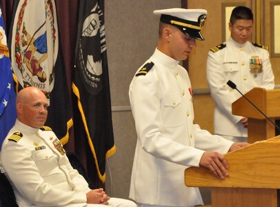 IMAGE: DAHLGREN, Va. (Sept. 11, 2018) - U.S. Navy Ensign Dillard Patton speaks to family, friends, and coworkers at his commissioning ceremony held at the Aegis Training and Readiness Center. Moments earlier, the NSWC Dahlgren Division System Safety Engineering Division civilian engineer was commissioned into the officer ranks of the Naval reserves through the Direct Commission Officer program. “We are victorious because we are faithful to these core values (honor, courage, and commitment) not only when serving on official duty, but also in our personal lives,” Patton told his audience, including Capt. Andrew Thomson, commissioning officer, left, and Lt. Cmdr. Warren Bong, master of ceremony. “I encourage every individual in this room to consider how these (U.S. Navy) core values impact your lives.”