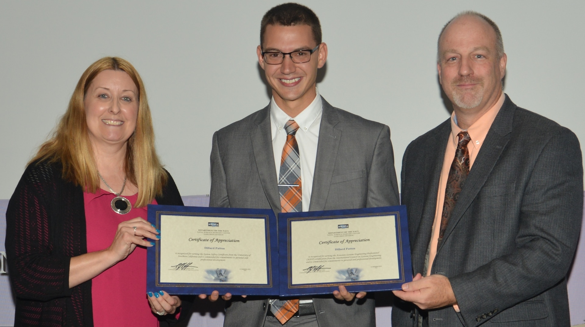 IMAGE: DAHLGREN, Va. (Sept. 21, 2018) – Dillard Patton receives certificates of appreciation from Naval Surface Warfare Center Dahlgren Division (NSWCDD) Acting Chief of Staff Terri Gray and Acting Deputy Technical Director Chris Clifford at the 2018 NSWCDD Academic Recognition Ceremony. Patton – commissioned into the Naval Reserves ten days earlier – was recognized for completing two professional certifications. He received a system safety certification from the University of Southern California and an associate systems engineering professional certification from the International Council on Systems Engineering.